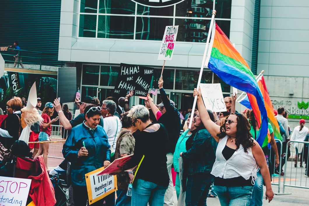 people holding flags and posters while standing in front of building